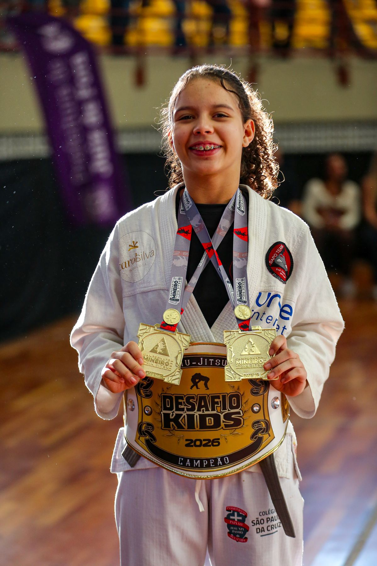 Ana Laura sorrindo, segurando o cinturão de campeã do Desafio Kids 2026